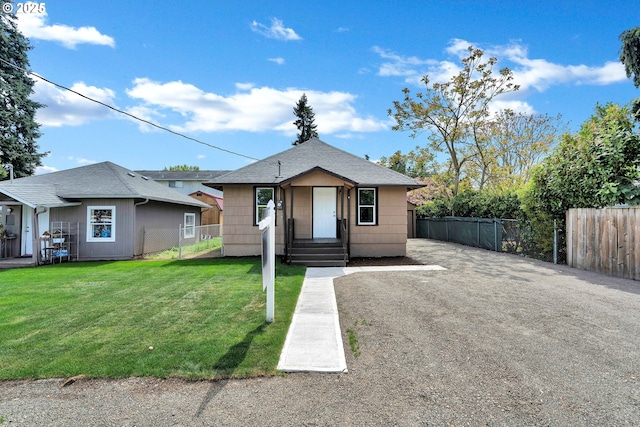 bungalow-style home featuring fence, roof with shingles, and a front lawn