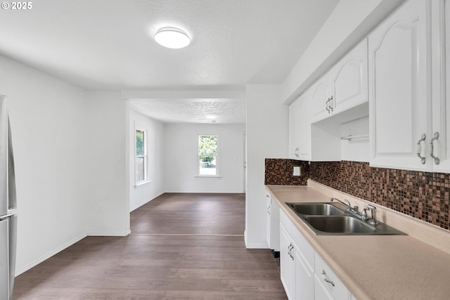 kitchen featuring white cabinets, a sink, a textured ceiling, decorative backsplash, and dark wood-type flooring