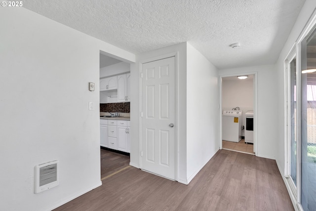 hallway with a sink, heating unit, wood finished floors, and a wealth of natural light