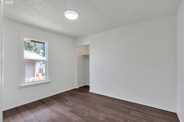 unfurnished bedroom with dark wood-type flooring, a textured ceiling, baseboards, and a closet