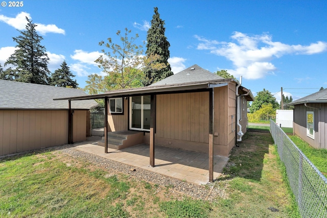 rear view of house featuring a shingled roof, a fenced backyard, a patio area, a lawn, and an outdoor structure