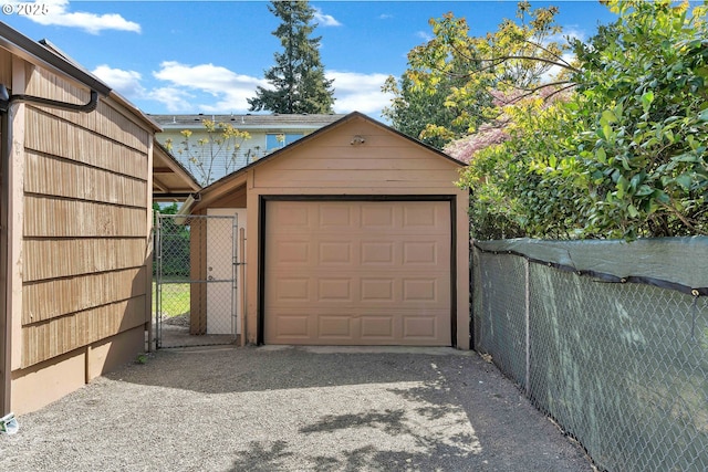 detached garage featuring a gate, aphalt driveway, and fence