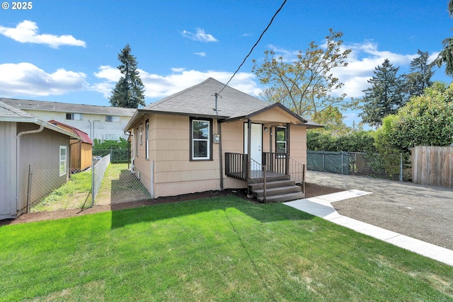 bungalow-style home featuring fence, roof with shingles, and a front yard
