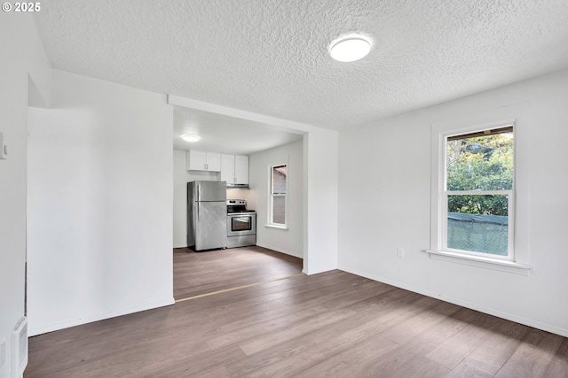 unfurnished living room with a textured ceiling, baseboards, and dark wood-type flooring