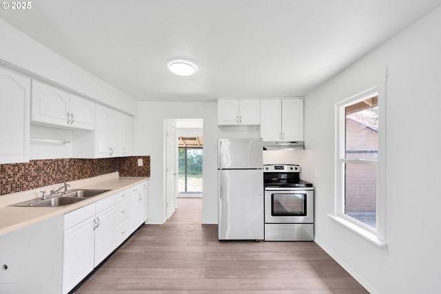 kitchen featuring white cabinets, appliances with stainless steel finishes, a sink, light wood-type flooring, and under cabinet range hood