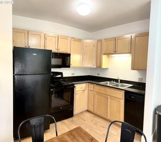 kitchen with a sink, dark countertops, black appliances, and light brown cabinetry