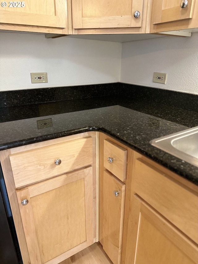 kitchen featuring a sink, light wood-style floors, dark stone countertops, and light brown cabinets