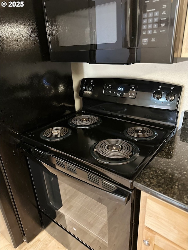 kitchen featuring dark stone counters and black appliances