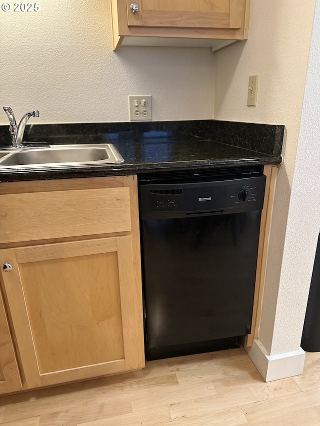 kitchen featuring a sink, dark countertops, black dishwasher, and light wood-type flooring