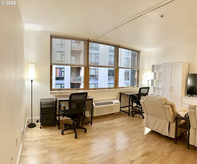 living room with a wall mounted air conditioner and light hardwood / wood-style floors