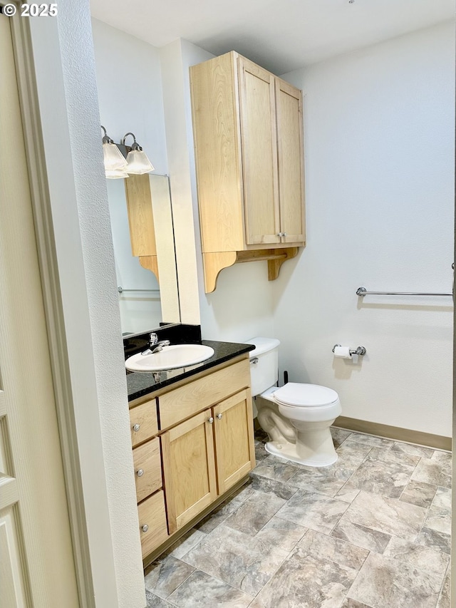 half bath with toilet, vanity, and baseboards
