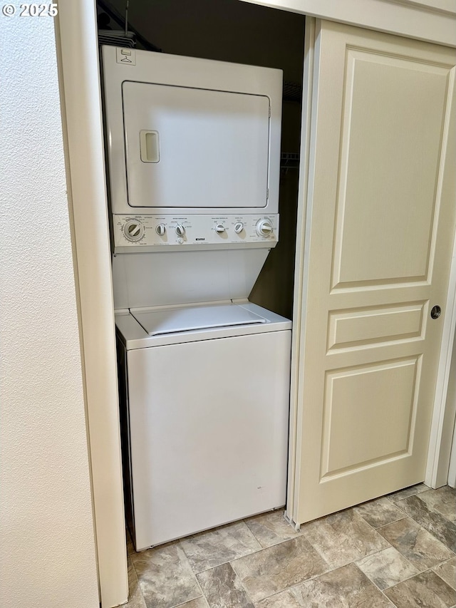 laundry room with stacked washer and clothes dryer, laundry area, and stone finish flooring
