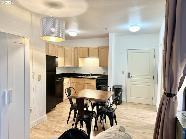 kitchen with dark countertops, light brown cabinetry, black appliances, and light wood-type flooring