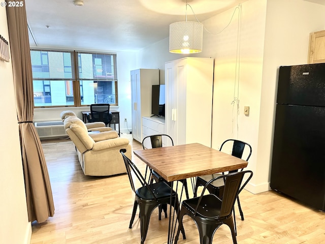 dining space with baseboards and light wood-type flooring