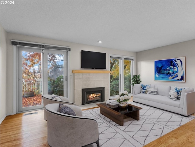 living room with a fireplace, light wood-type flooring, and a textured ceiling