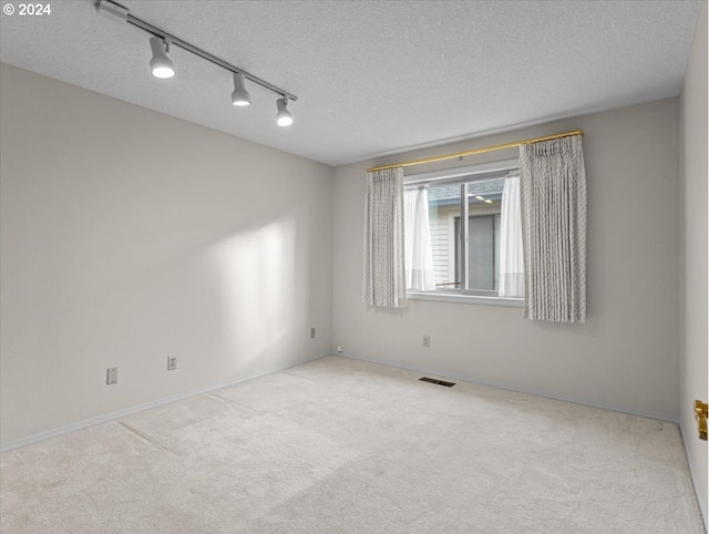 carpeted spare room featuring track lighting and a textured ceiling