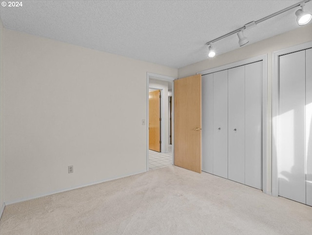 unfurnished bedroom with a textured ceiling and light carpet