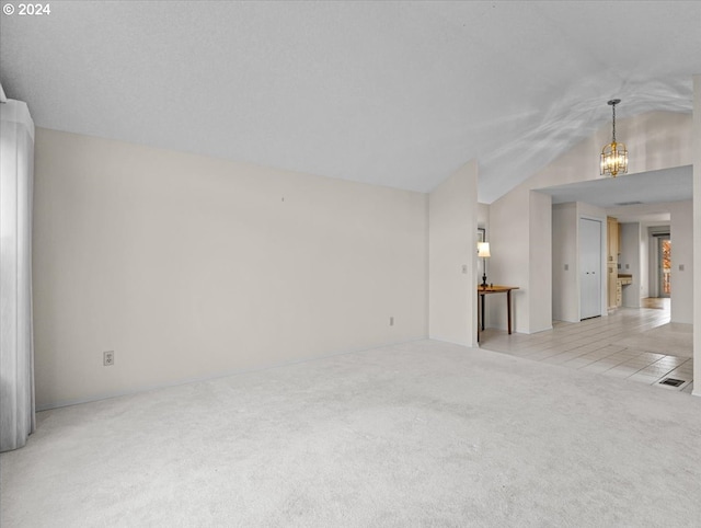 carpeted empty room featuring vaulted ceiling and a notable chandelier