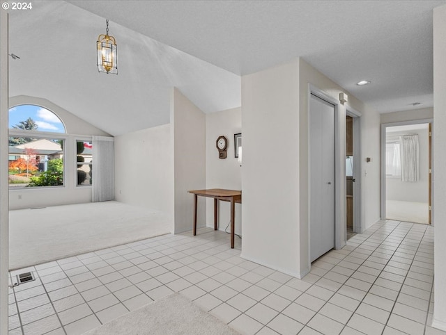 interior space featuring a textured ceiling, vaulted ceiling, and light tile patterned flooring