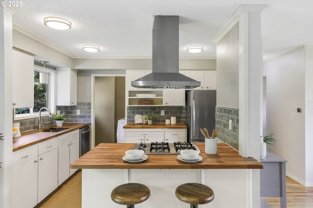 kitchen featuring island exhaust hood, ornamental molding, wooden counters, and stainless steel appliances