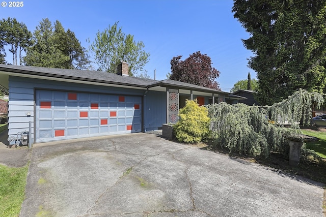 single story home featuring concrete driveway, a chimney, and an attached garage