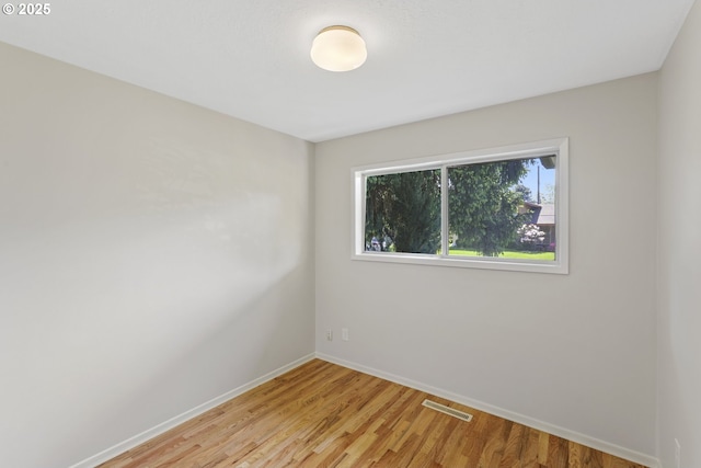 empty room with visible vents, baseboards, and light wood finished floors