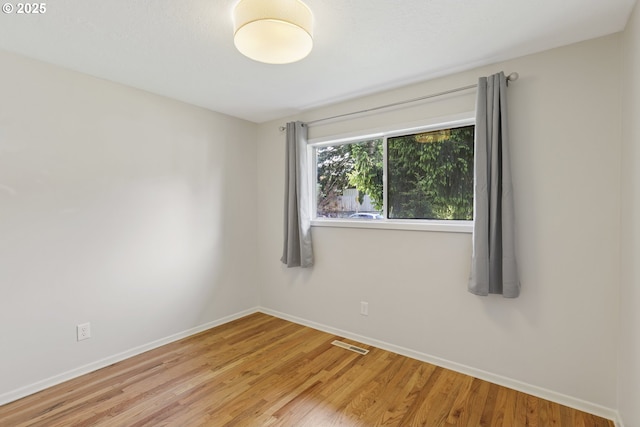 unfurnished room featuring visible vents, baseboards, and wood finished floors