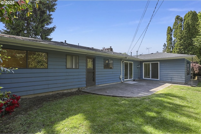 back of house featuring a yard, a chimney, and a patio area