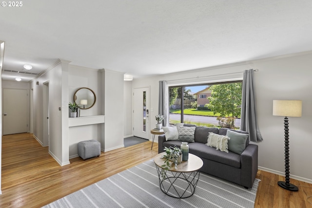 living room featuring crown molding, baseboards, visible vents, and wood finished floors