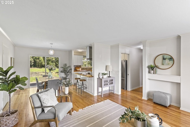 living area with crown molding, baseboards, and light wood-style floors