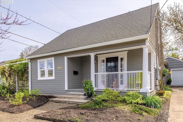 view of front of home with a garage, roof with shingles, an outbuilding, and covered porch