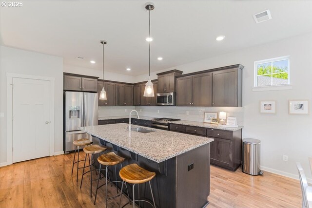 7010 SW Barr Ln, Tualatin, OR 97062 - kitchen featuring appliances with stainless steel finishes, dark brown cabinetry, backsplash, light wood-style floors, and recessed lighting