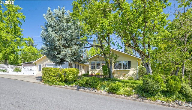 view of front of house featuring fence, driveway, and a garage