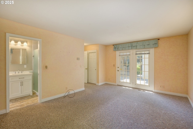 spare room featuring baseboards, a sink, and light carpet