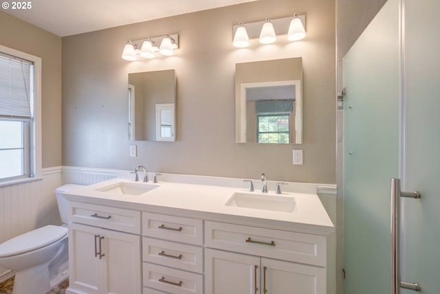 full bath featuring double vanity, toilet, wainscoting, and a sink
