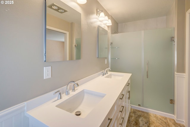 bathroom featuring double vanity, a sink, and a stall shower
