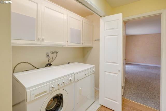 clothes washing area with baseboards, washer and dryer, cabinet space, and light colored carpet