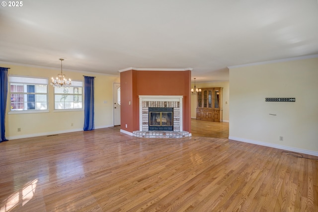 unfurnished living room featuring light wood-style floors, an inviting chandelier, baseboards, and a fireplace