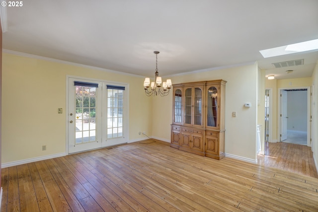 unfurnished dining area with visible vents, a skylight, light wood-type flooring, baseboards, and a notable chandelier