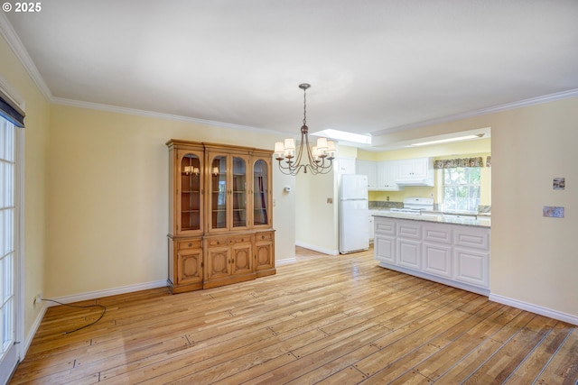 unfurnished dining area with crown molding, baseboards, light wood finished floors, and a notable chandelier