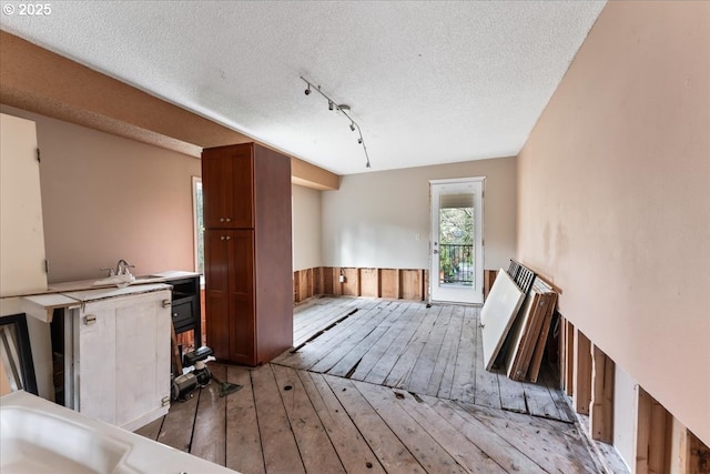 interior space featuring a wainscoted wall, a textured ceiling, and light wood-style floors