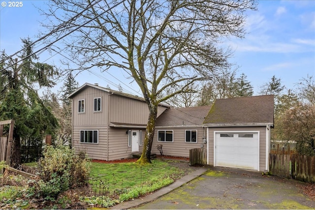 traditional-style house with an attached garage, a front lawn, fence, roof with shingles, and driveway