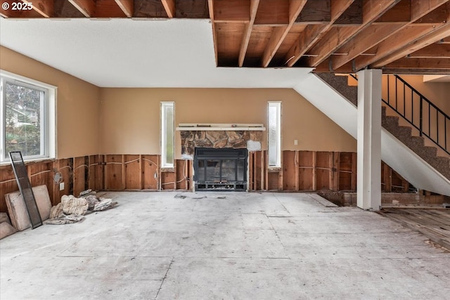 unfurnished living room with a stone fireplace and stairs