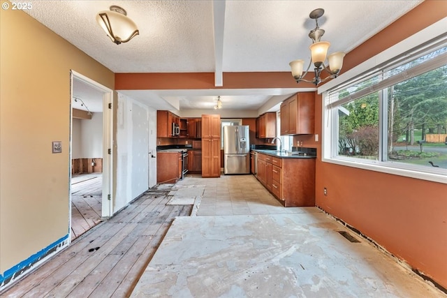 kitchen with a sink, dark countertops, appliances with stainless steel finishes, and brown cabinetry