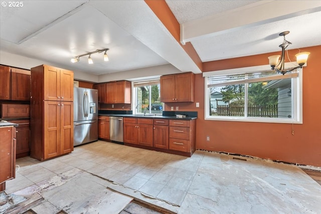 kitchen with dark countertops, a chandelier, stainless steel appliances, brown cabinetry, and a textured ceiling