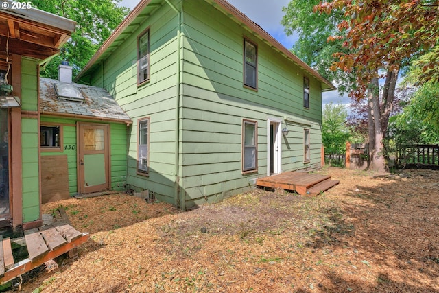 rear view of house featuring fence and a chimney