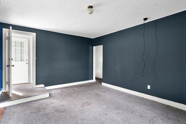 carpeted empty room featuring a textured ceiling and baseboards