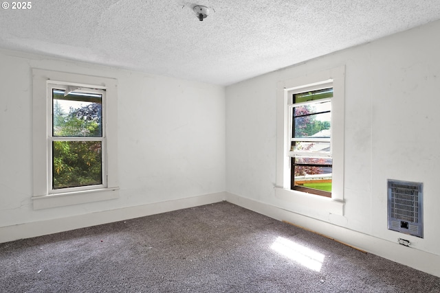 empty room featuring heating unit, carpet flooring, a textured ceiling, and a pendent fire sprinkler