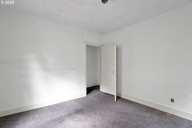 empty room with carpet floors, a textured ceiling, and baseboards