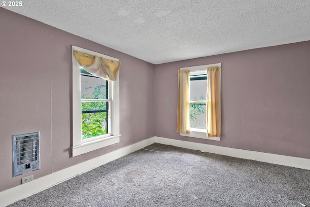carpeted spare room featuring a textured ceiling and heating unit